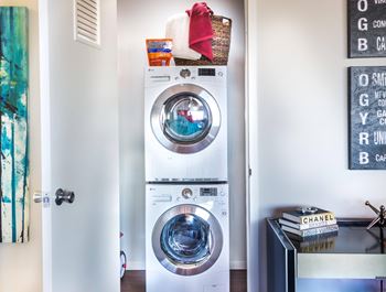 A white front loading washing machine with a basket on top of it.